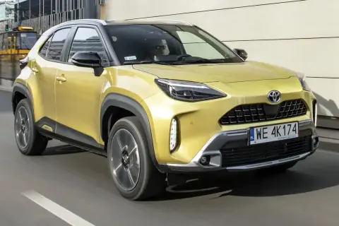 Żółty Toyota Yaris Cross na drodze, z widocznym kierowcą. Czy jego wady są widoczne na pierwszy rzut oka?