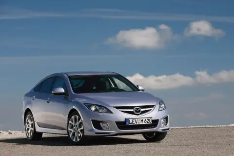 Srebrna Mazda 6 2.0 benzyna na tle błękitnego nieba z chmurami.