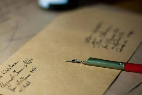 Plume et encre sur papier kraft. On peut écrire famille sur une enveloppe pour envoyer des nouvelles.