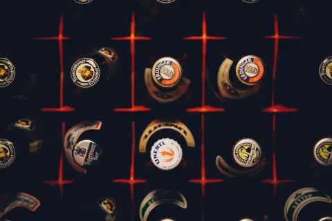 Kapsle piwne różnych marek, w tym Erdinger i Franziskaner, tworzą mozaikę. Każda kapsla to mały patron piwa, opowiadający historię smaku.