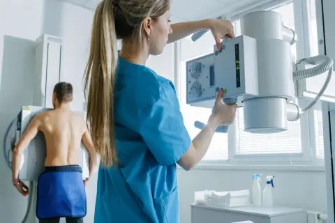 Technik przygotowuje aparat RTG do badania pacjenta. To właśnie RTG co to jest, czyli rentgenografia.
