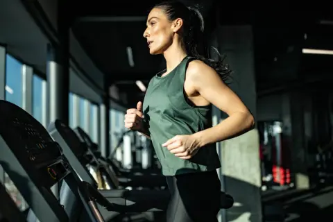 Eine Frau läuft auf einem Laufband im Fitnessstudio. Sie trainiert intensiv und zeigt, was ein Laufband für die Ausdauer bringt.