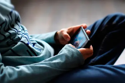 Ein digitaler Mensch, vertieft in sein Smartphone. Die Hände halten das Gerät, während der Blick auf den Bildschirm gerichtet ist.