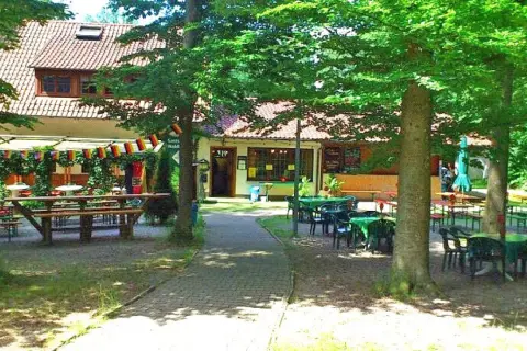 Idyllischer Biergarten mit vielen Tischen und Bänken unter Bäumen, dekoriert mit Deutschlandflaggen. Einladend für ein Treffen im Waldheim Backnang.