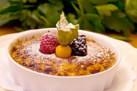 En krämig crema catalana toppad med bär och pudrat socker, en ljuvlig dessert.