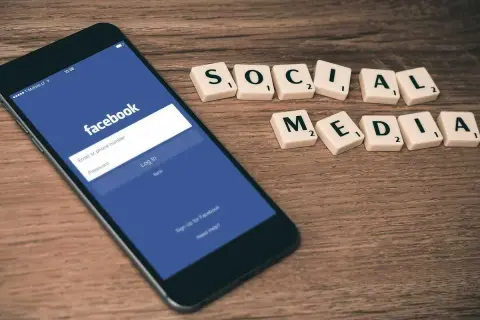 Smartfon z ekranem logowania Facebooka i kafelki z napisem "SOCIAL MEDIA".