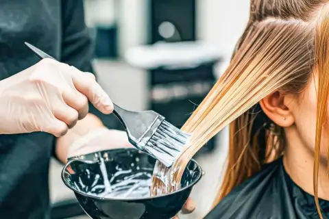 Hårstylist applicerar färg för att skapa slingor i grått hår.