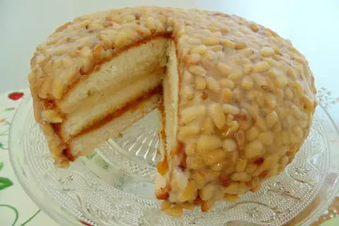 Tarta de piñones tradicional, con capas de bizcocho y mermelada, cubierta de piñones caramelizados. ¡Un dulce irresistible!