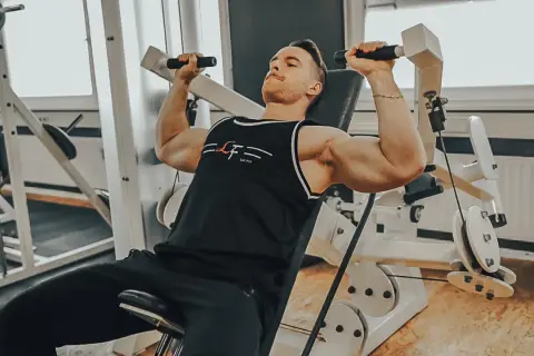 Mann trainiert Schultern an einer Maschine, ein intensiver superset workout für maximale Ergebnisse.