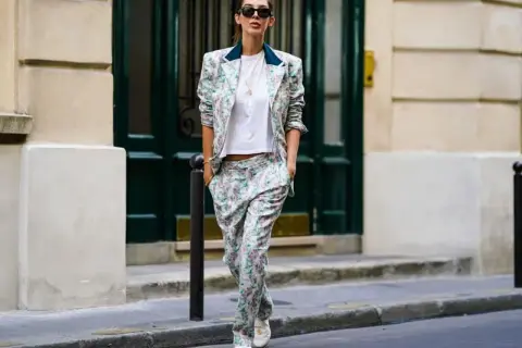 Donna con tailleur floreale e scarpe basse cammina per strada, con un'aria disinvolta e chic.