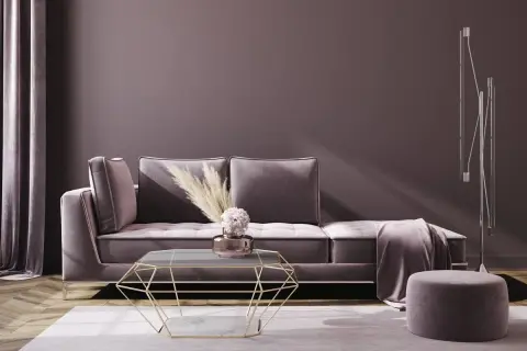 Ein luxuriöses Sofa in Mauve-Farbe mit einem geometrischen Couchtisch und einem runden Hocker.