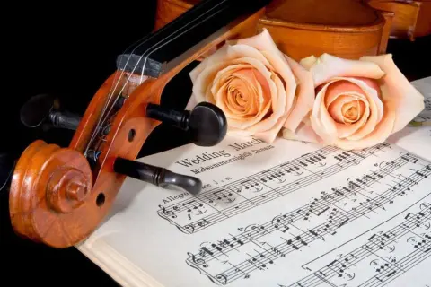 Violon posé sur des partitions de "Wedding March", orné de roses. Une belle évocation d'un mariage thème musique.