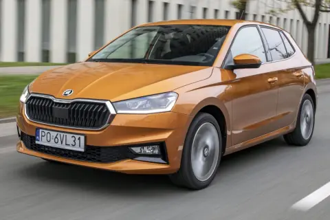 Pomarańczowa Skoda Fabia 2021 pędzi po drodze, jej reflektory ostro świecą, a felgi wirują w ruchu.