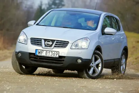 Srebrny Nissan Qashqai 2.0 benzyna na drodze szutrowej, kierowca za kierownicą.