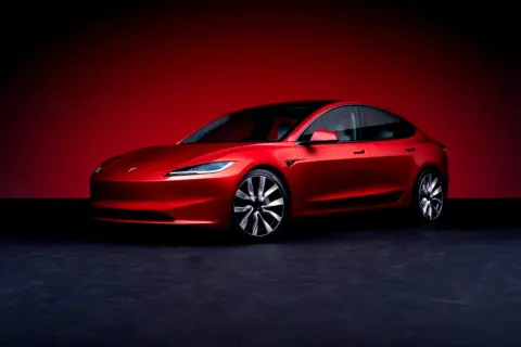 Un Tesla Model 3 rojo brillante, listo para demostrar su bajo consumo.