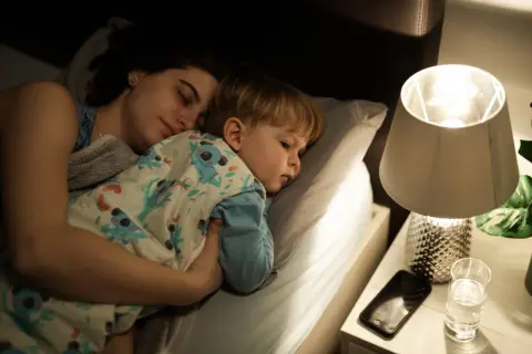 Mamma e figlio dormono abbracciati a letto, avvolti in una coperta con koala. Un momento di pace prima che i miei figli si sveglino.