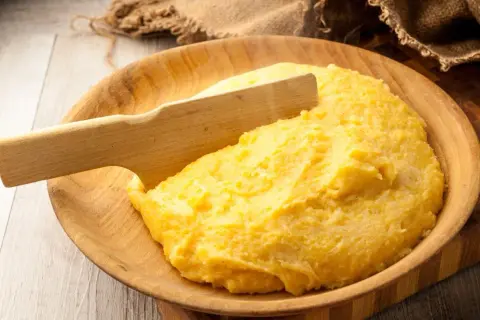 Gorąca polenta, czyli co to jest? Aromatyczna, żółta kaszka kukurydziana podana w drewnianej misie, gotowa do jedzenia.