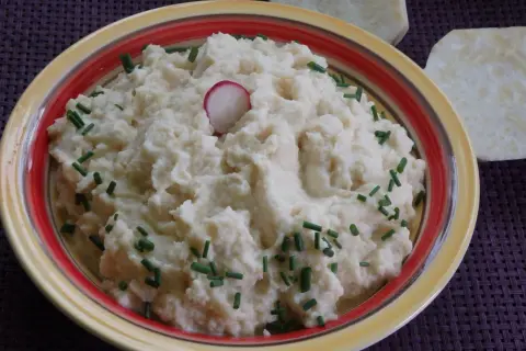 Puszyste puree z selera, udekorowane szczypiorkiem i plasterkiem rzodkiewki, prezentuje się apetycznie.