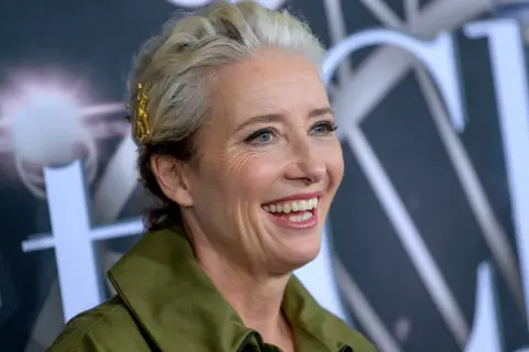 Uśmiechnięta Emma Thompson, znana z wielu wspaniałych filmów, z blond włosami ozdobionymi złotą spinką.