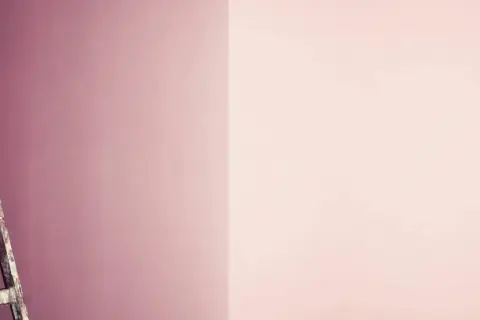 Alte Leiter steht vor einer Wand, die in zwei Rosatöne geteilt ist. Perfekt für das **Wandfarbe mischen** für ein neues Projekt.