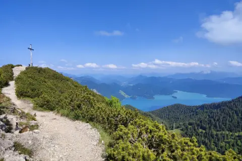 Gipfelkreuz nach einer Heimgarten Wanderung mit Blick auf einen türkisfarbenen See und Berge.