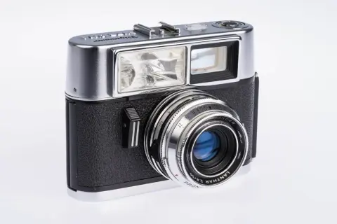 Klasyczny, srebrno-czarny aparat Voigtländer. Ten pierwszy aparat fotograficzny z lat 50. ma charakterystyczny obiektyw i wbudowaną lampę błyskową.