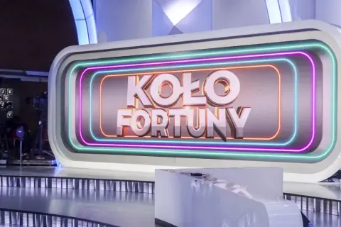 Logo "Koło Fortuny" na tle studia telewizyjnego z neonowym obramowaniem.