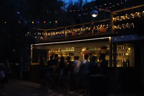 Nocna imprezowa ulica w Warszawie. Bar z kolorowymi światłami i ludźmi cieszącymi się wieczorem.