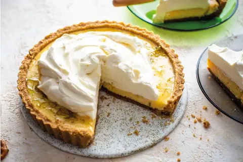 En krämig key lime pie med fluffig grädde på toppen, en bit serverad på en grön tallrik.