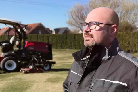 Mann mit Brille, der auf Rasenmäher blickt. Neue Wege für Quereinsteiger in Berufe in der Natur.