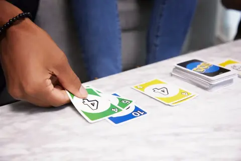 Ręka trzyma karty gry DOS. Na stole leżą karty z numerami 4, 6 i 10.