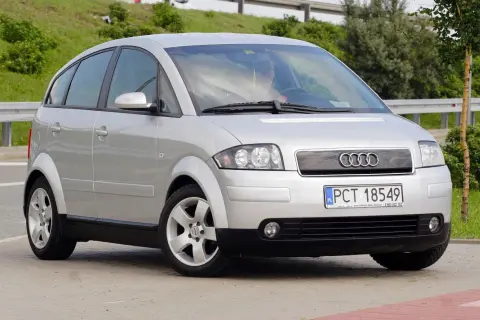 Srebrny Audi A2, kompaktowy samochód z charakterystycznymi, zaokrąglonymi liniami, prezentuje swoje a2 wymiary na tle zieleni.