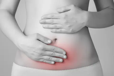 Mani sul ventre con area rossa che indica dolore. L'endometriosi può causare invalidità e sofferenza cronica.