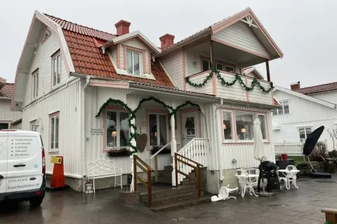 Vitt hus med rosa detaljer och juldekorationer. Skylt visar "Reception Restaurang". Kanske en titt på restaurang Solliden meny?