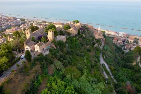 Borgo medievale su una collina affacciata sul mare Adriatico, con il lungomare di Cupra Marittima in lontananza.
