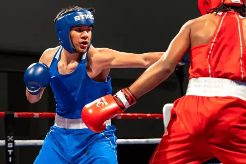 Two young boxers in a ring, one in blue, the other in red. This image shows the intensity of amateur boxing, where age limits are strictly enforced for safety.