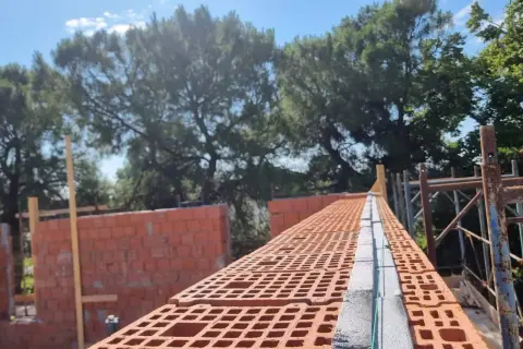 Costruzione di una muratura portante in laterizio, con mattoni forati rossi e blocchi in cemento.