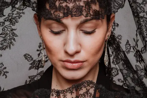 Mujer con peinados de mantilla, luciendo pendientes largos y un abanico de encaje.