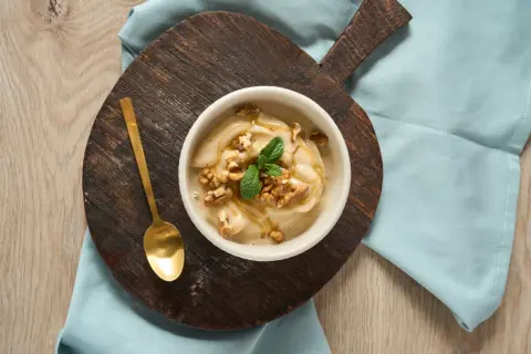 En skål med krämig nice cream, toppad med valnötter, mynta och honung. En gyllene sked ligger bredvid.
