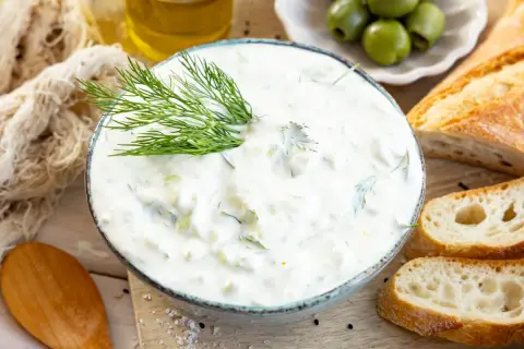Cremiger Tzatziki mit Dill, serviert mit Baguette und Oliven. Ein einfaches Tzatziki Rezept für den Sommer.