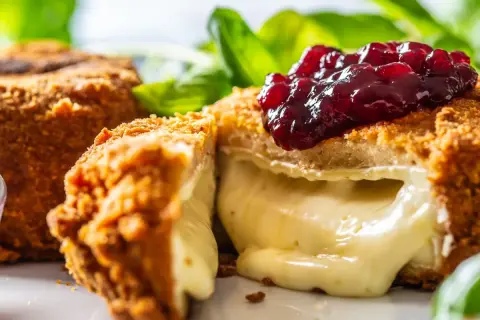 Chrupiący camembert w panierce, z rozpływającym się serem w środku, polany konfiturą z owoców leśnych. Idealny na przekąskę.