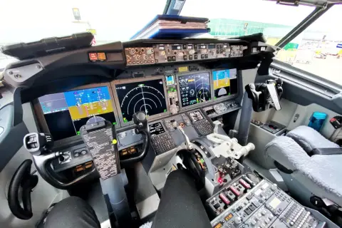 Kokpit samolotu Boeing 737 z widokiem na panele sterowania, ekrany nawigacyjne i yoke.
