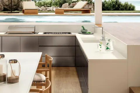 Moderna encimera para exterior con barbacoa integrada, junto a una piscina y tumbonas.
