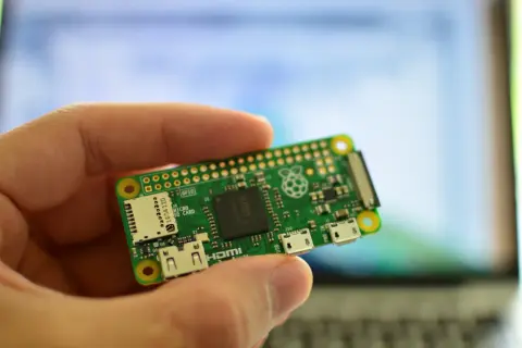 Dłoń trzyma miniaturową płytkę Raspberry Pi Zero W, gotową do projektów. To wszechstronne raspberry pi zastosowanie w elektronice.