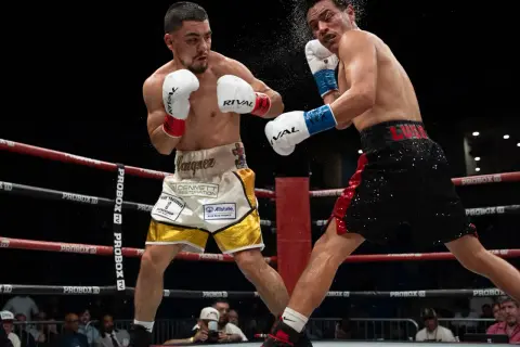 Two boxers clash in the ring. One lands a punch, sending sweat flying. This intense moment could lead to a unanimous decision in boxing if all judges score it for one fighter.