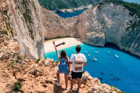 Couple admirant la baie de Navagio, une des plus belles plages des top 5 des îles grecques. L'eau turquoise et les falaises blanches sont spectaculaires.