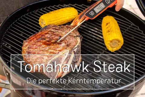 Ein saftiges Tomahawk Steak wird auf dem Grill mit Maiskolben gegrillt. Ein Fleischthermometer misst die Kerntemperatur für das perfekte Ergebnis.