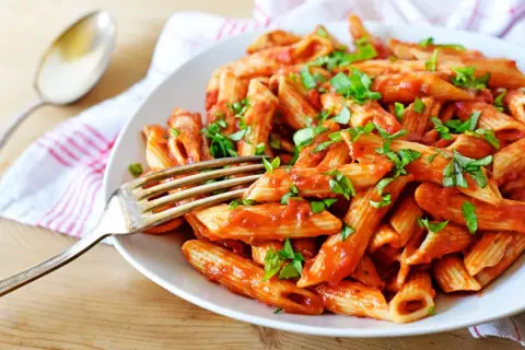 Penne w pikantnym sosie pomidorowym, posypane świeżą bazylią. Idealne spaghetti arrabiata na obiad.