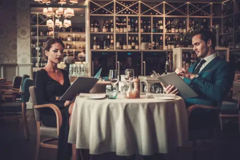 Elegancka para przy stoliku w restauracji, przegląda karty dań. Krótki dialog w restauracji po angielsku, co zamówić?