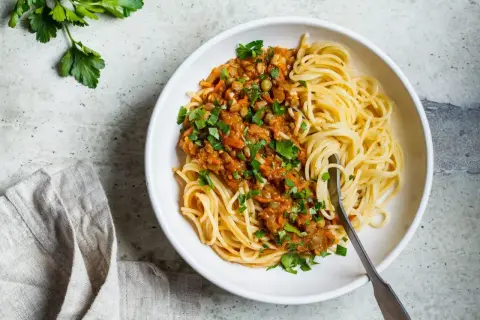 Porcja spaghetti bolognese z soczewicą, posypana natką pietruszki. Idealna na obiad, znasz już jej spaghetti bolognese kcal?